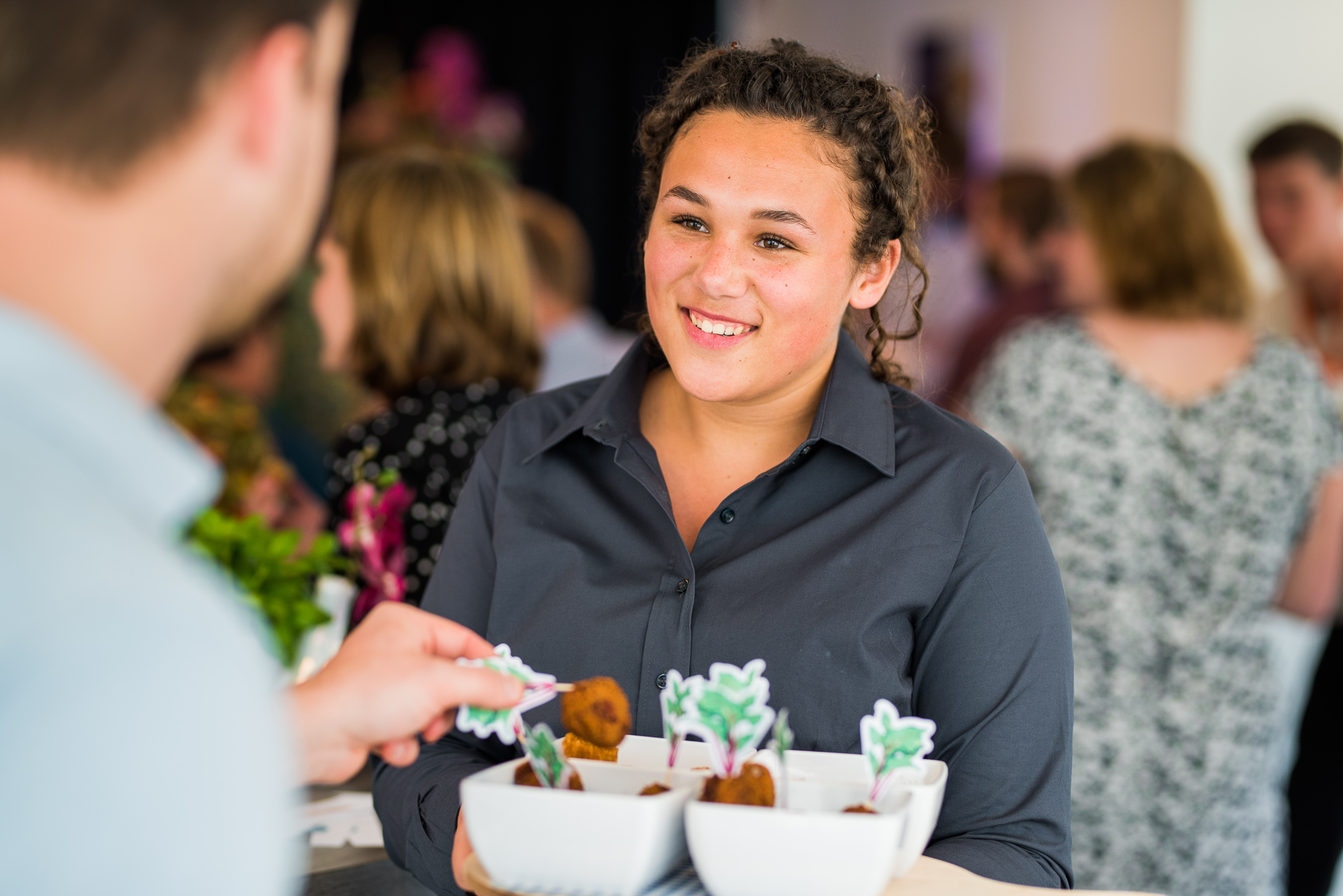 glimlachende medewerker serveert bitterballen