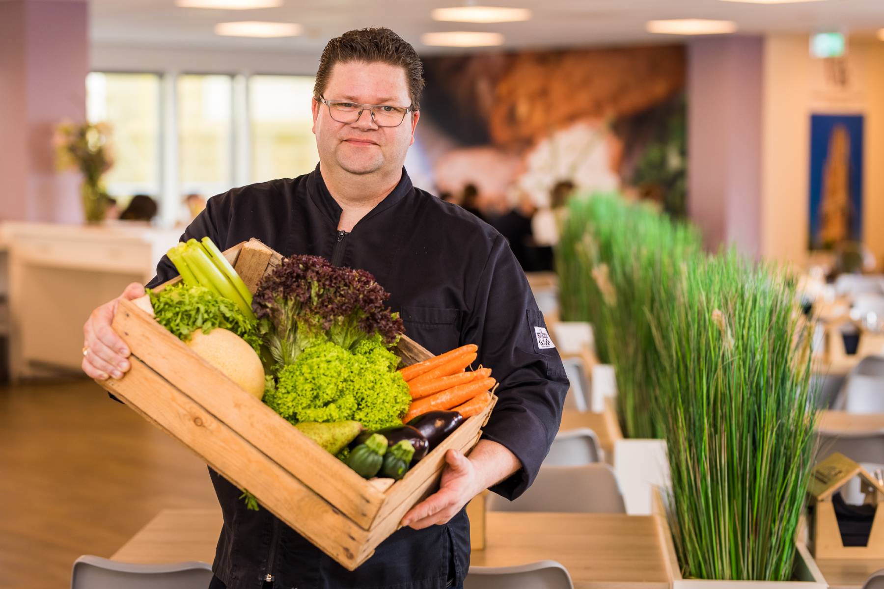 kok houdt houten krat met groente vast