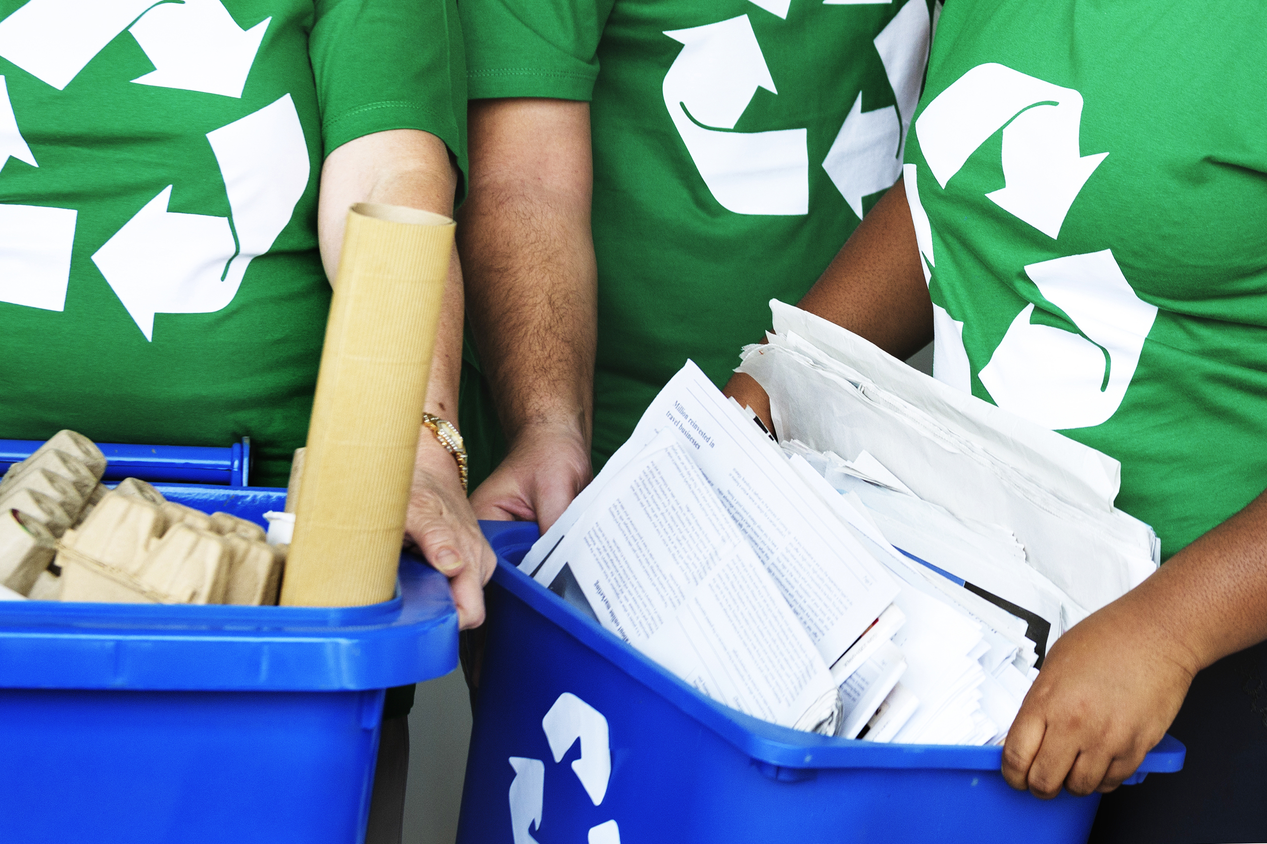 blauwe bakken met papier en groene T-shirts met recycle logo
